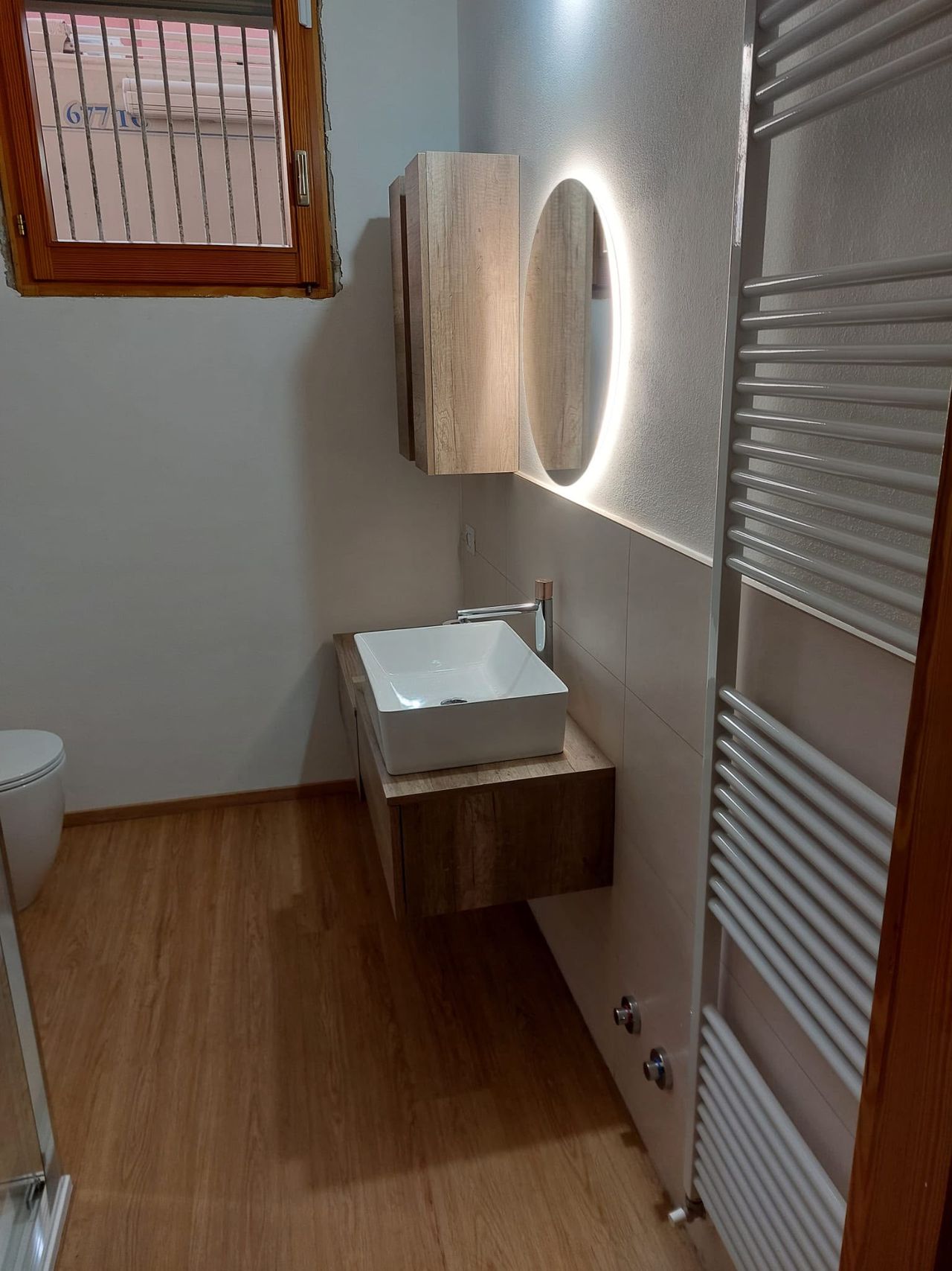 Bagno con mobile compatto, lavabo e specchio illuminato